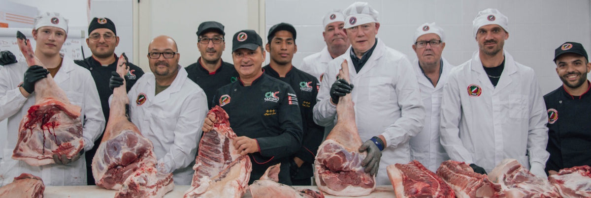 Michael Combs with chefs and instructors of the Stagionello Academy holding whole pork legs during a hands-on salumi masterclass