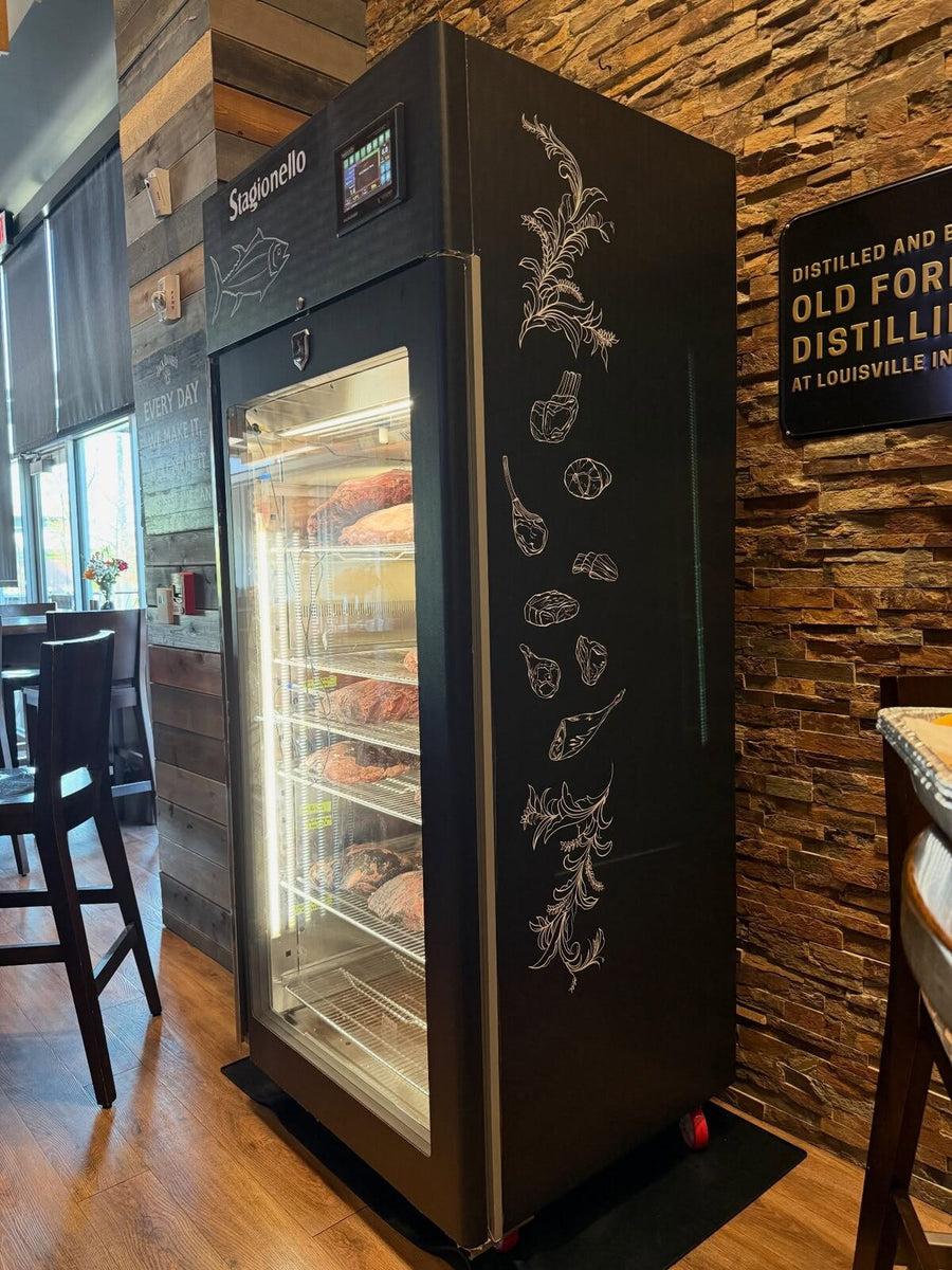 Customer's Stagionello curing cabinet with custom line artwork on the side panel, in a restaurant dining room